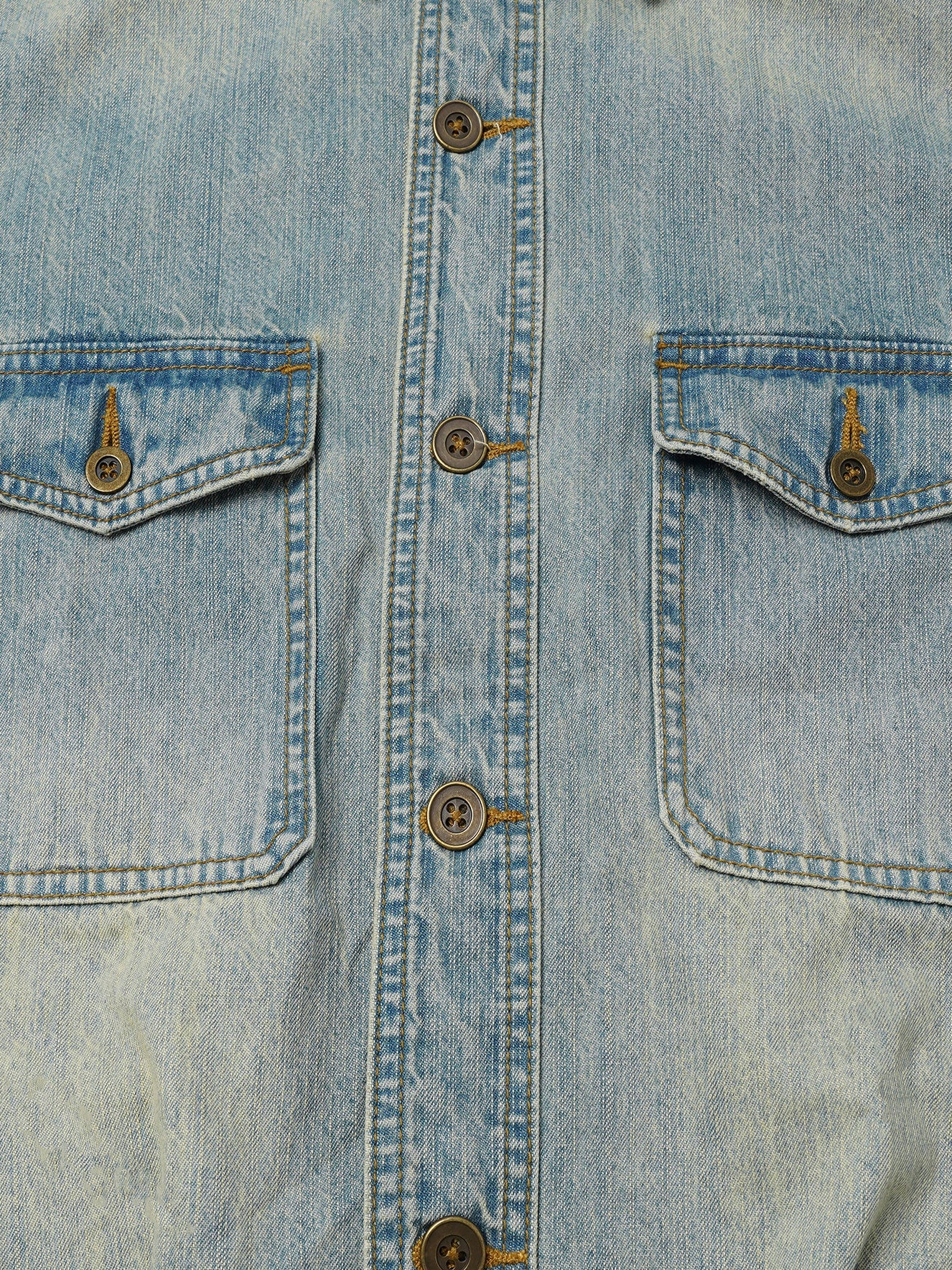 Close-up of the washed denim, chest flap pockets and metal buttons