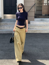 Woman walking down a sunlit side street in a navy fitted crop knit tee and wide trousers