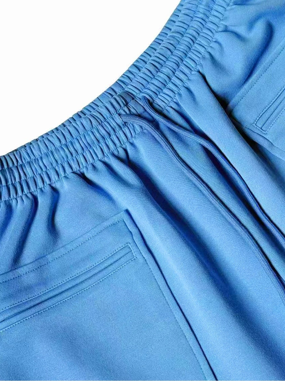 Close-up of the elastic drawstring waistband and patch pocket of blue gradient wide pants