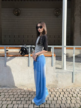 Woman in blue gradient drawstring wide pants and a raglan tee standing on a sunlit cobblestone street
