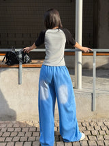 Back view of blue gradient drawstring wide pants on a cobblestone street