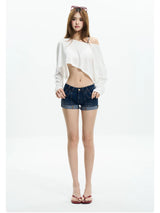 Woman in a white off shoulder crop tee and low-rise denim shorts