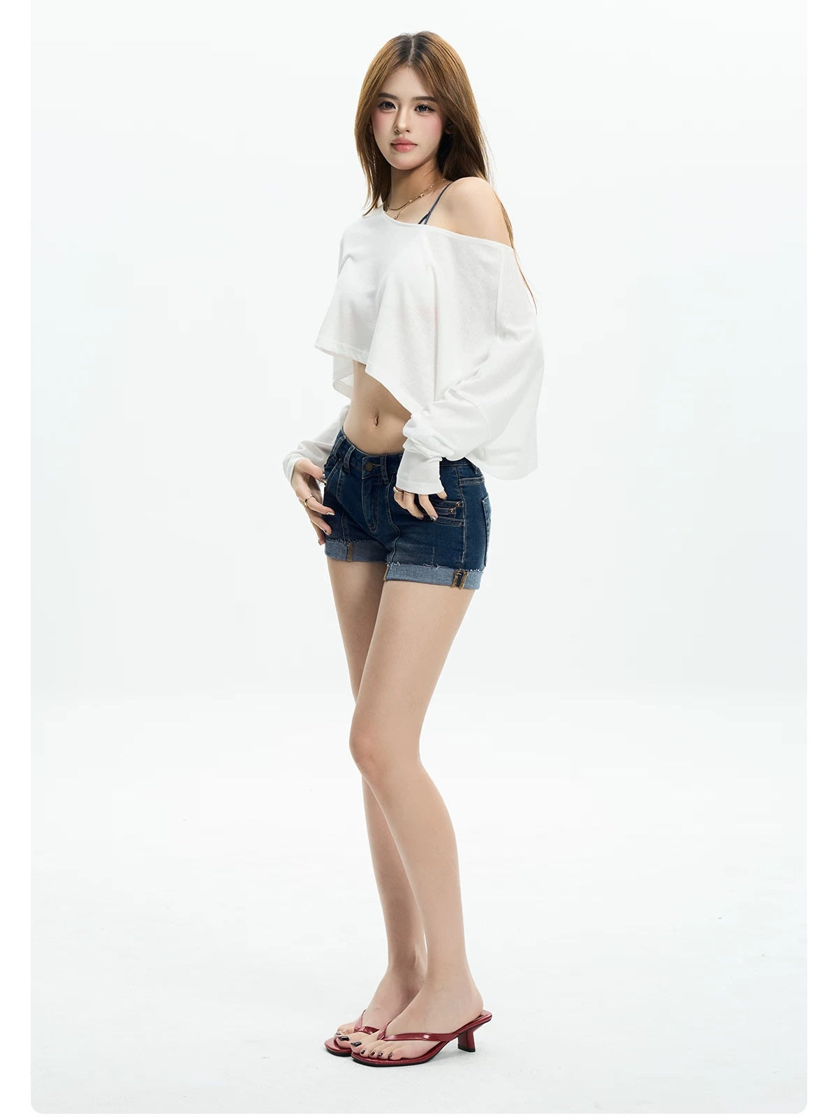 Woman turning in a white off shoulder crop tee and denim shorts